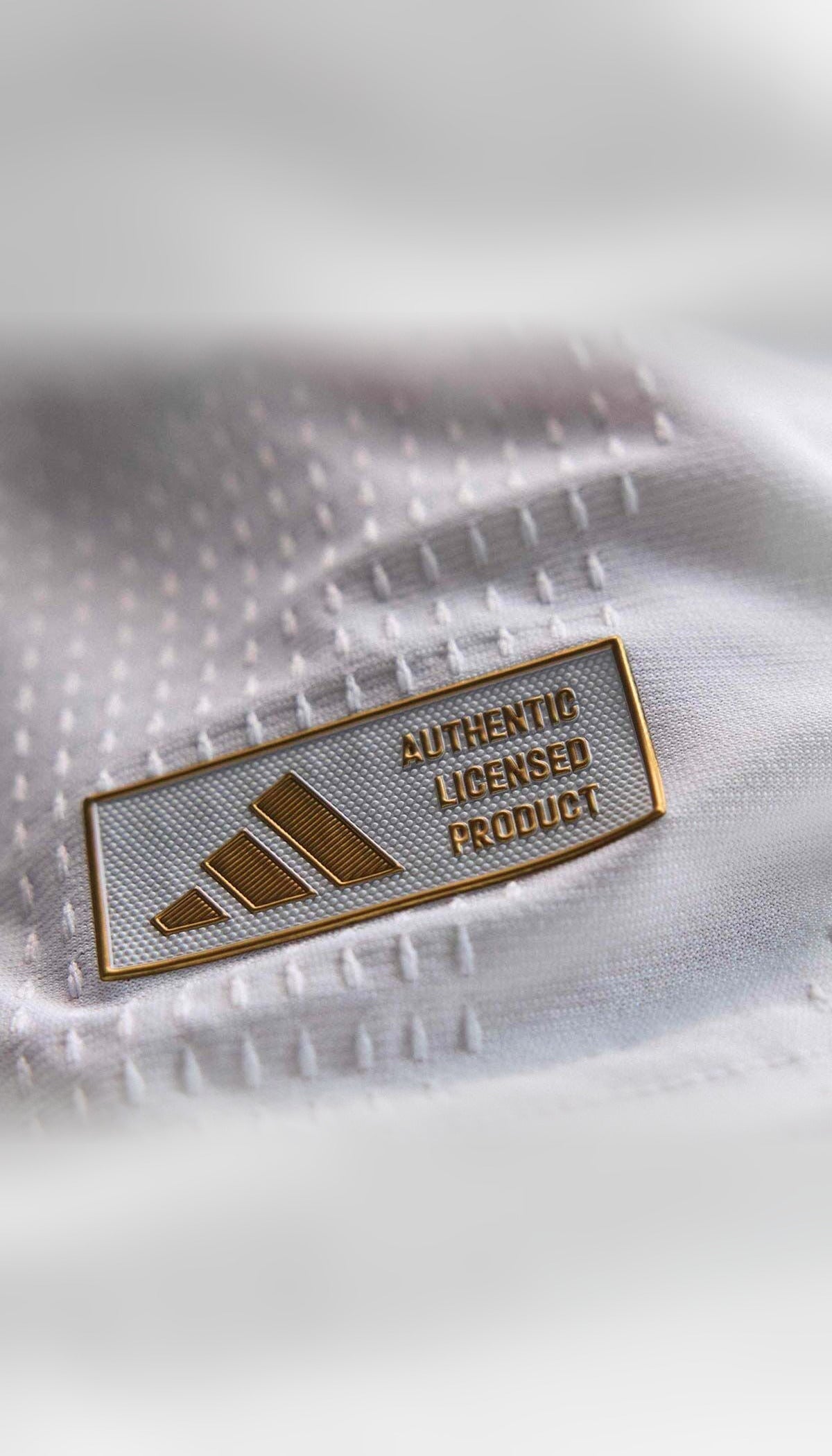 Real Madrid local 2026/27 versión jugador — detalle de la etiqueta inferior del jersey